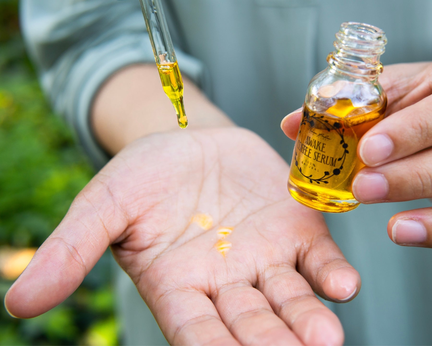 A close-up shot of the Awake Coffee Serum being dispensed into an open palm from the dropper.