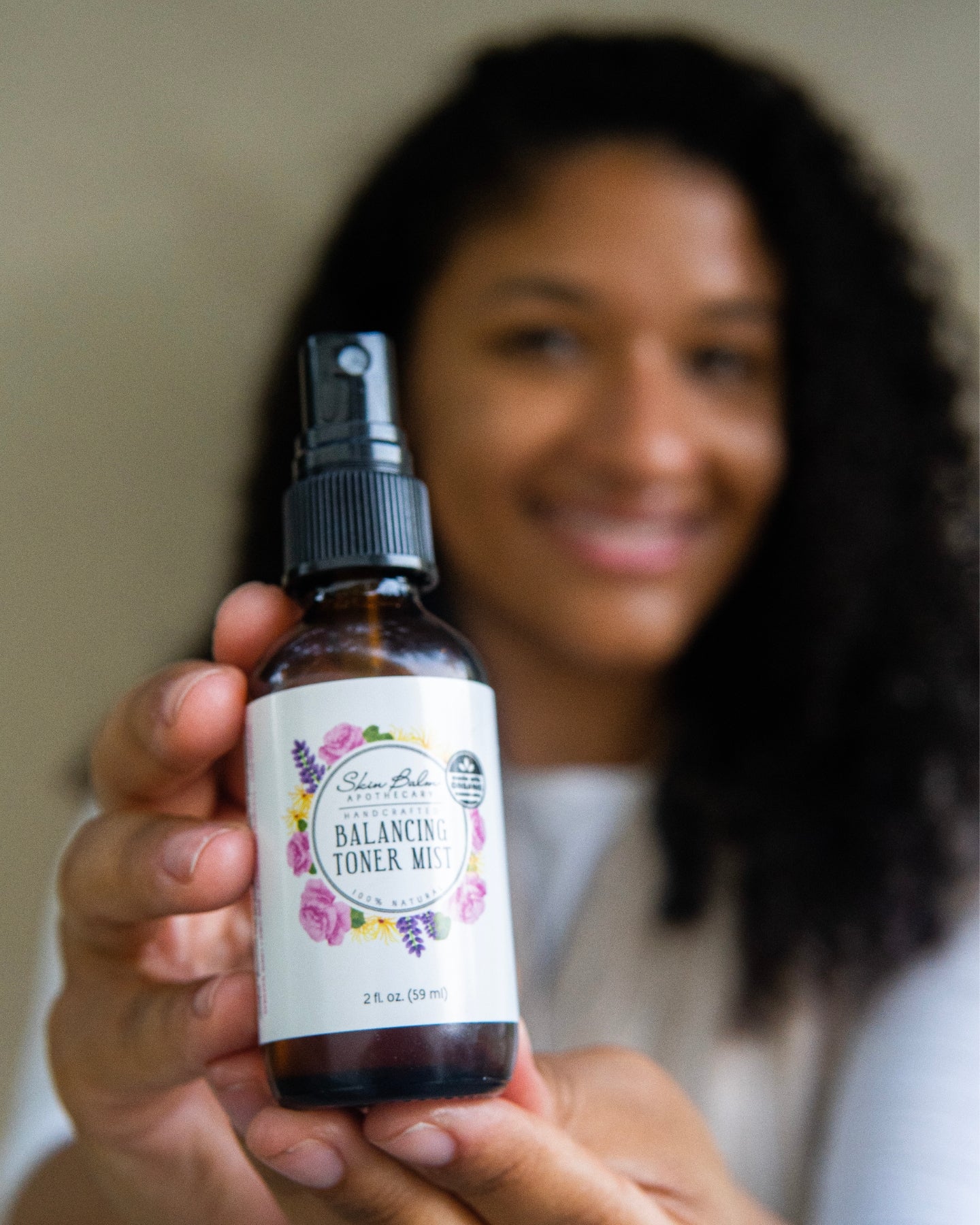 Balancing Toner Mist focused in the foreground with a smiling woman blurred in the background.