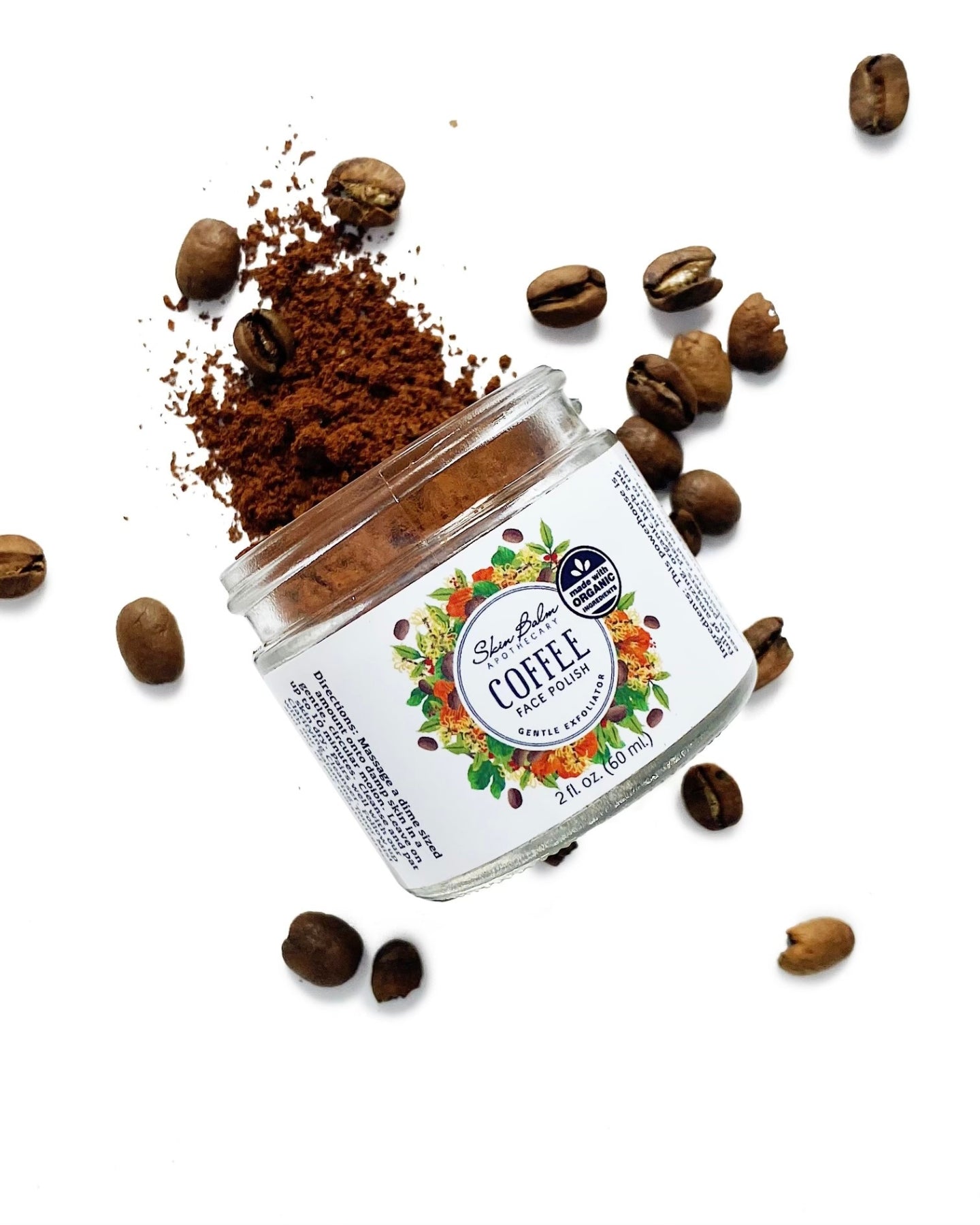 Coffee Face Polish surrounded by coffee beans against a white background.