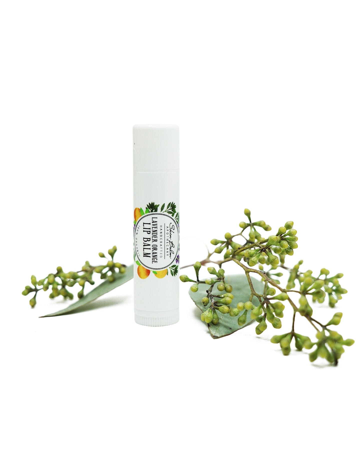 Lavender Orange Lip Balm with green foliage against a white background.