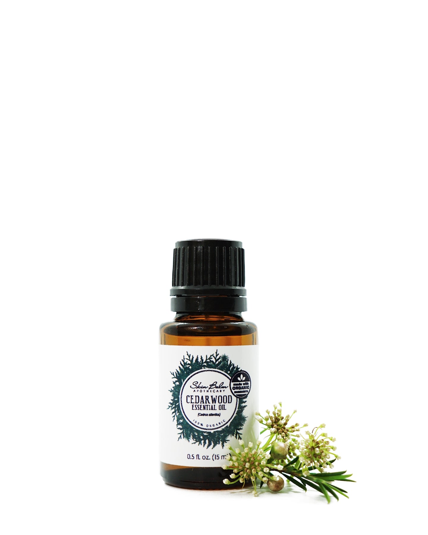 Organic Cedarwood Essential Oil with an evergreen stem against a white background.