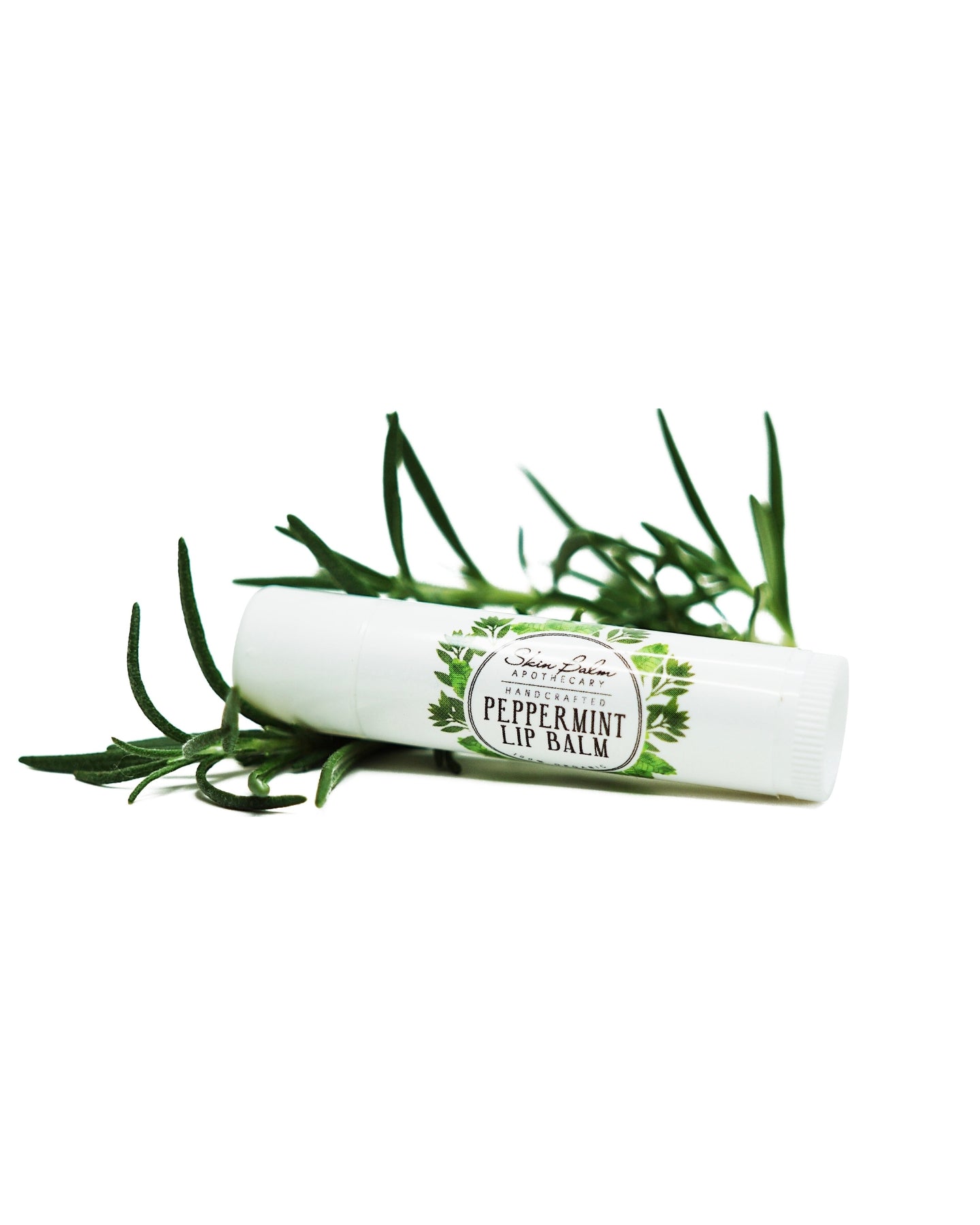 Peppermint Lip Balm with green foliage against a white background.