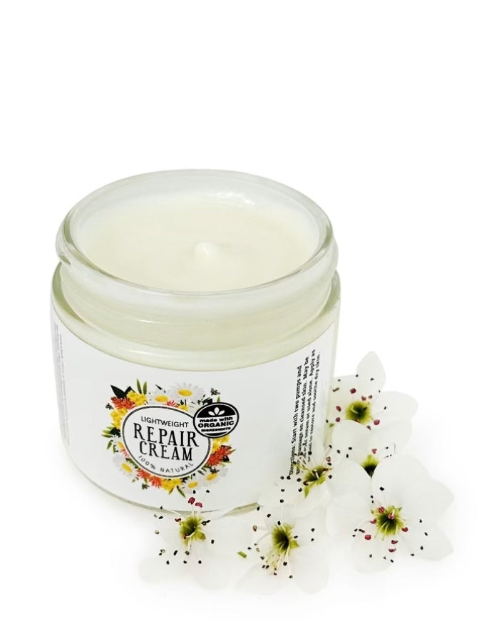 Repair Cream without the lid surrounded by white flowers against a white background.