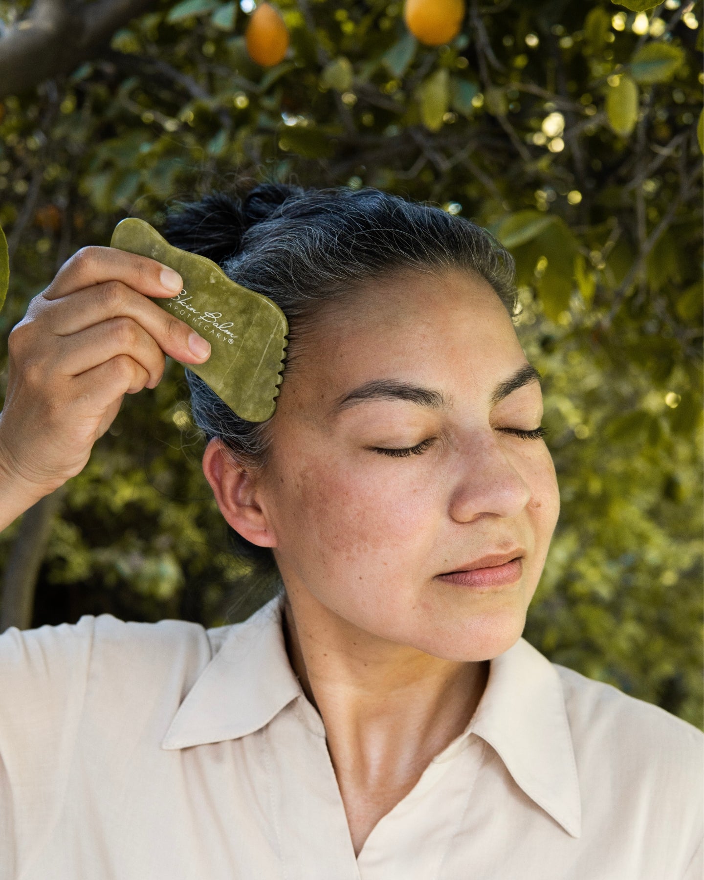 A woman uses the Jade Facial Stone on her face.