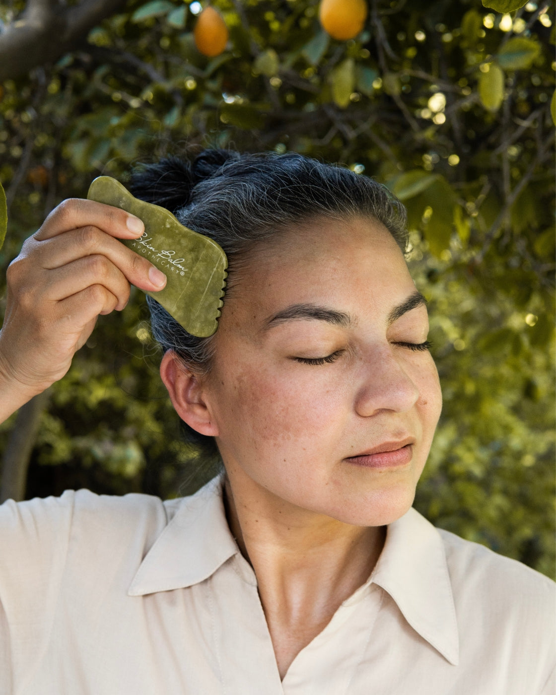 A woman uses the Jade Facial Stone on her face.