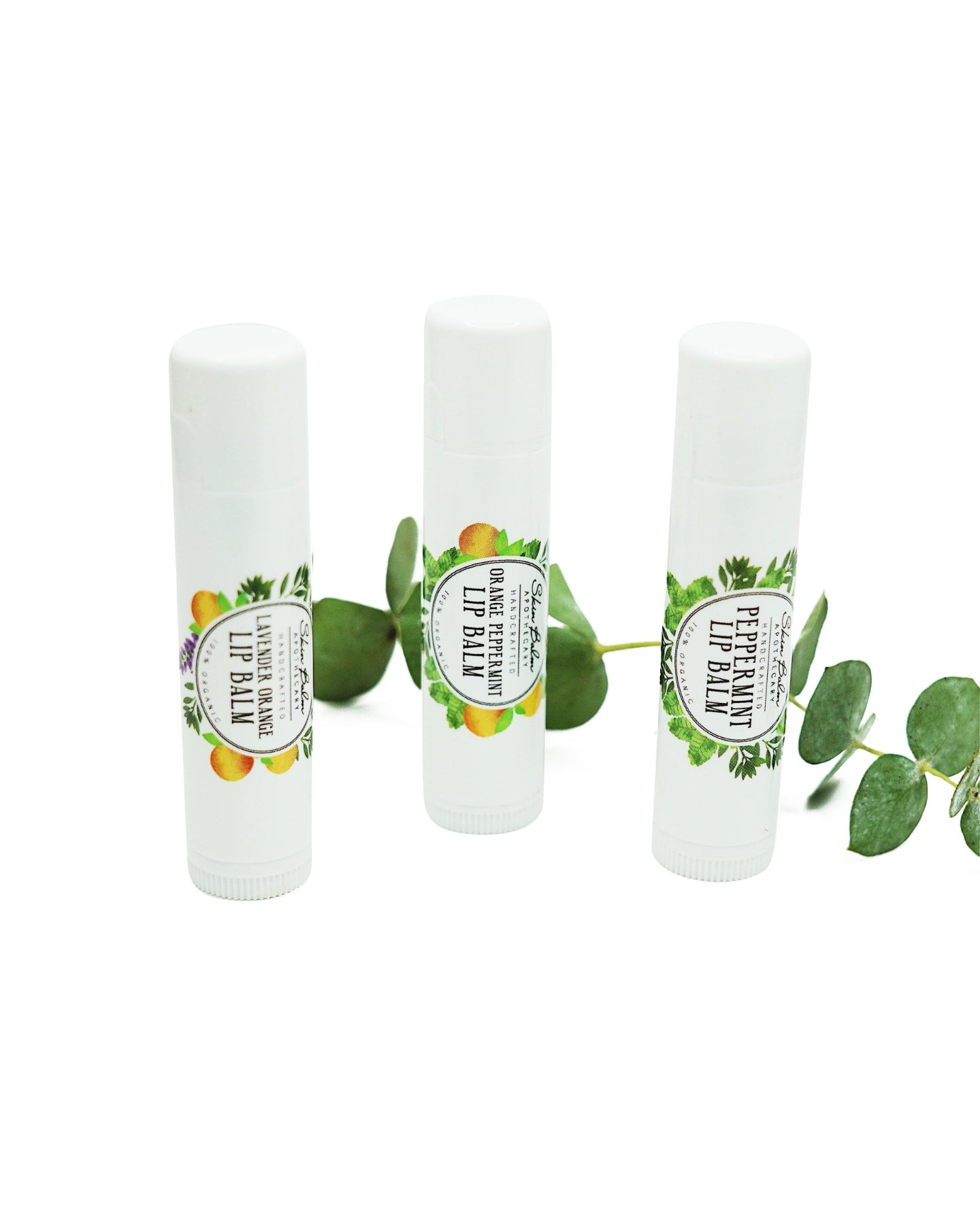 Lip Balm Trio with green foliage against a white background.