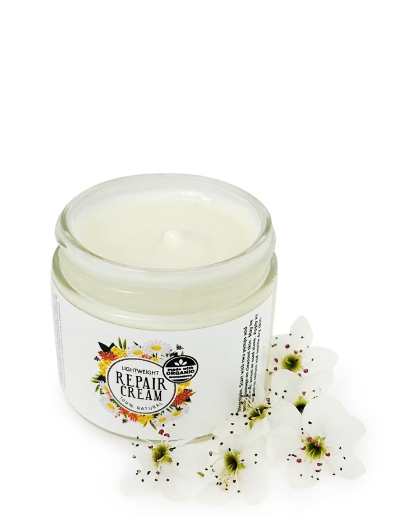 Repair Cream without the lid surrounded by white flowers against a white background.